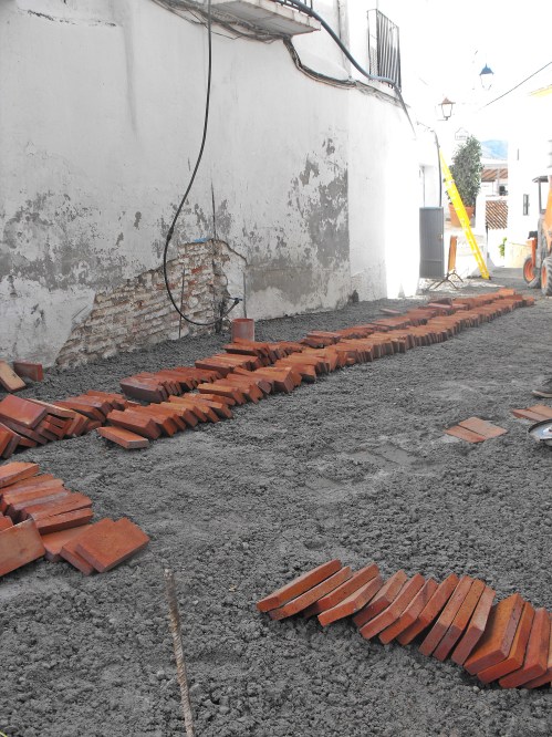 First strip out the old concrete and lay out the ladrillos (thin bricks). Get a team to fix the plumbing/drainage. Turn off the village water arbitrarily and with no notice